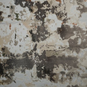 May include: A woven area rug featuring an abstract, mottled pattern in shades of charcoal gray, beige, cream, and off-white. The design includes small, scattered accents of muted green and burnt orange, creating a textured, layered appearance.