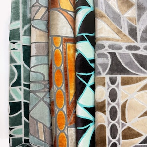 May include: Five vertical fabric swatches featuring a geometric pattern of interlocking shapes and lines. The colors include deep green, light blue-gray, vibrant orange, black with teal accents, and a neutral palette of beige, brown, and gray tones.