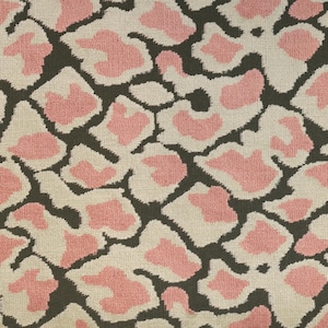 Op de afbeelding: Een textielstof met een herhalend abstract dierenpatroon. Het ontwerp bestaat uit onregelmatige, afgeronde vormen in zachtroze en crème, omlijnd en gescheiden door een donker antracietgrijze achtergrond met een zichtbare geweven textuur.