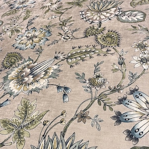May include: A beige fabric featuring a repeating botanical pattern with stylized flowers and leaves in shades of muted blue, sage green, and dark brown. The design includes intricate floral motifs, winding vines, and detailed foliage.