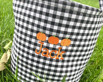 May include: Black and white gingham fabric trick or treat bucket with orange embroidered pumpkins and the name "Jack" in orange thread.