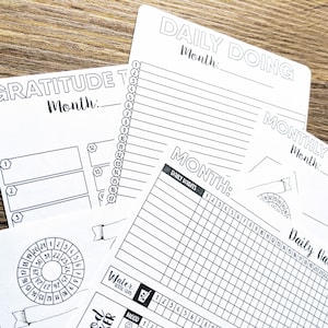 May include: Four black and white printable planner pages with headings for "Daily Doing", "Gratitude Tracker", "Monthly Memo", and "Month". The pages include sections for daily habits, water intake, mood tracking, and a gratitude list.
