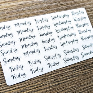 May include: A sheet of white stickers with black text. The stickers feature the days of the week: Sunday, Monday, Tuesday, Wednesday, Thursday, Friday, and Saturday.