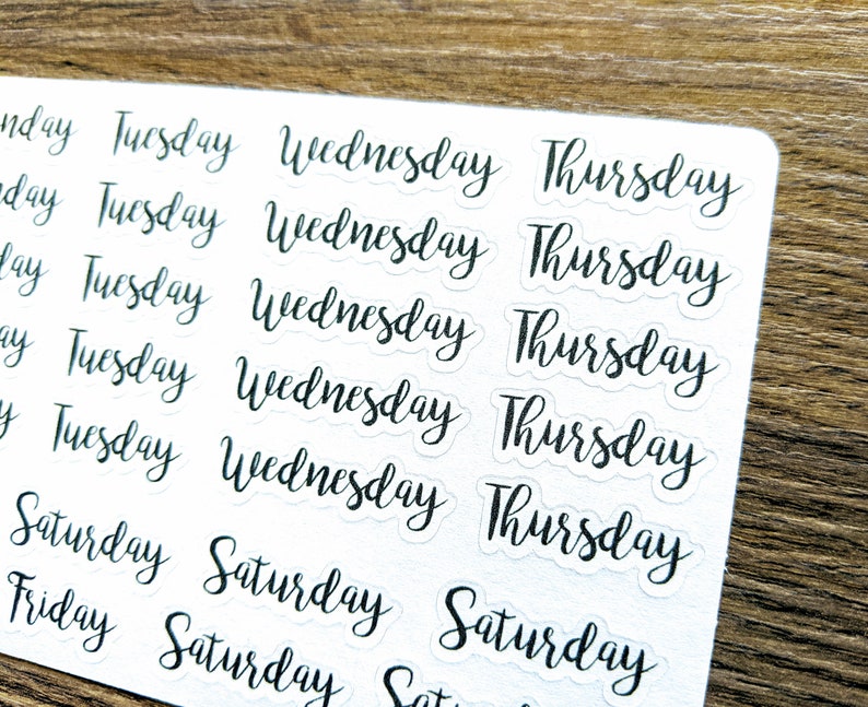 May include: A sheet of clear stickers with black handwritten text. The stickers feature the days of the week: Monday, Tuesday, Wednesday, Thursday, Friday, Saturday.