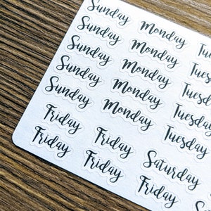 May include: A sheet of clear stickers with the days of the week written in black cursive. The stickers are arranged in rows and columns, with each day of the week repeated multiple times.
