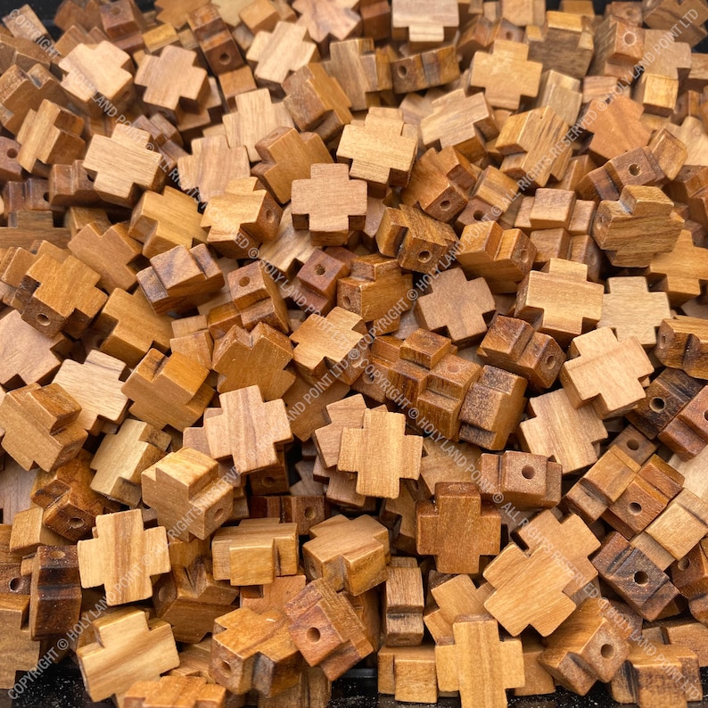 Pu&ograve; includere: Un mucchio di piccole perline di legno a forma di croce. Le perline sono di colore marrone chiaro e hanno una finitura liscia e lucida.
