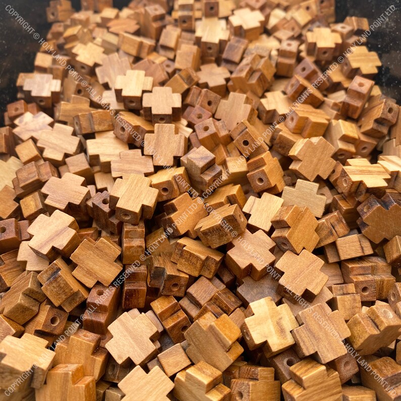 Pu&ograve; includere: Un grande mucchio di piccole perline di legno a forma di croce. Le perline sono di colore marrone chiaro e hanno una finitura liscia e naturale.