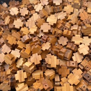 Pu&ograve; includere: Un'immagine ravvicinata di un mucchio di piccole croci di legno. Le croci sono di colore marrone chiaro e hanno una finitura liscia e lucida.