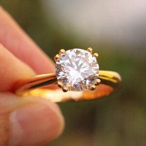 Op de afbeelding: Een gouden ring met een grote, heldere, ronde diamant.