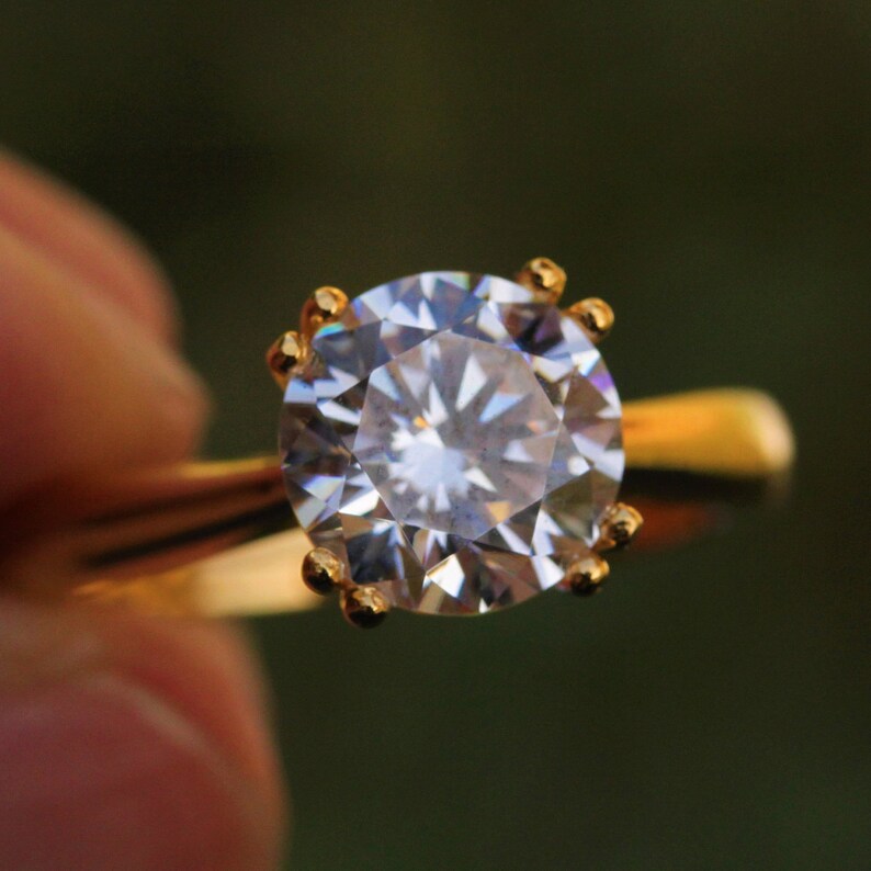 May include: A gold ring with a large, clear, round diamond.