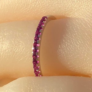 May include: A delicate gold band ring with a row of small pink gemstones.