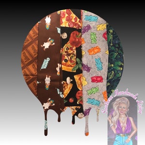 Puede incluir: Un conjunto de cinco tiras de tela con diferentes patrones. Las tiras están dispuestas en un círculo y gotean hacia abajo como cera derretida. Los patrones incluyen barras de chocolate, patos de dibujos animados, rebanadas de pizza, ositos de goma y extraterrestres. El texto "Southern Handmade Living" es visible en la esquina inferior derecha de la imagen.