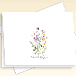 May include: White card with a watercolor illustration of a bouquet of pink, purple, blue, and yellow wildflowers. The text "Elizabeth Meyers" is written in cursive at the bottom of the card.