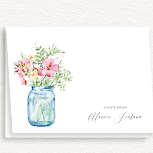May include: A white card with a watercolor illustration of a blue mason jar filled with pink and yellow flowers. The text "A note from Marion Fontana" is printed at the bottom of the card.