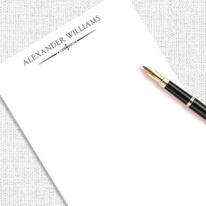 May include: A white notepad with a black pen and the text "ALEXANDER WILLIAMS" at the top.