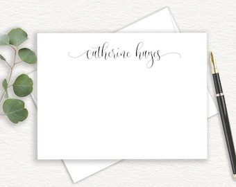May include: A white rectangular stationery card featuring the name catherine hayes printed in black cursive script at the top center, accompanied by a matching white envelope and a black fountain pen with gold accents.