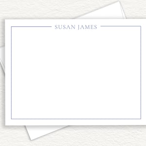 May include: A white stationery card with a blue border and the name "SUSAN JAMES" printed in the center.