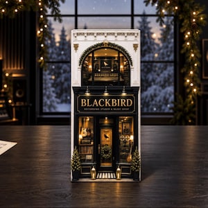 May include: A miniature Blackbird Recording Studio and Music Shop building model featuring a white upper facade with an arched window and a black storefront with gold lettering. The interior displays musical instruments and recording equipment.