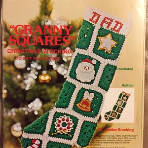 May include: A green and white Christmas stocking with a granny square design. The stocking is crocheted and features a variety of festive appliques, including a star, a bell, a wreath, and a candy cane. The stocking is labeled "DAD" and "MOM" and is 21 inches long. The kit includes yarn, felt, sequins, beads, ribbon, and instructions.
