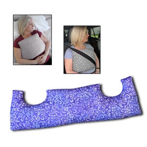 May include: A blue floral patterned pillow with a distinctive shape, designed for comfort. The pillow is shown in use in two scenarios: as a sleep aid and with a seatbelt. The pillow's dimensions are not visible.