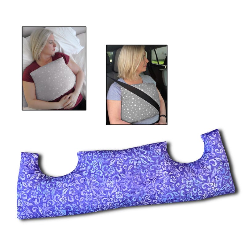 May include: A blue floral patterned pillow with a distinctive shape, designed for comfort. The pillow is shown in use in two scenarios: as a sleep aid and with a seatbelt. The pillow's dimensions are not visible.