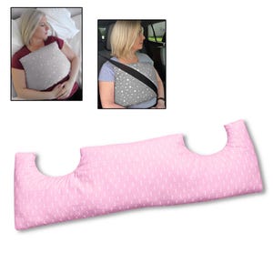 May include: A pink pillow with a white dotted pattern and curved cutouts. The pillow is shown in use in a car and in bed. The pillow is designed to provide support and comfort.