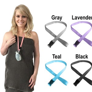 Puede incluir: Una colecci&oacute;n de correas de tela ajustables con hebillas de pl&aacute;stico de liberaci&oacute;n lateral, disponibles en gris, lavanda, verde azulado y negro. Cada correa presenta un dise&ntilde;o de bucle y se muestra junto a una prenda envolvente gris oscuro.