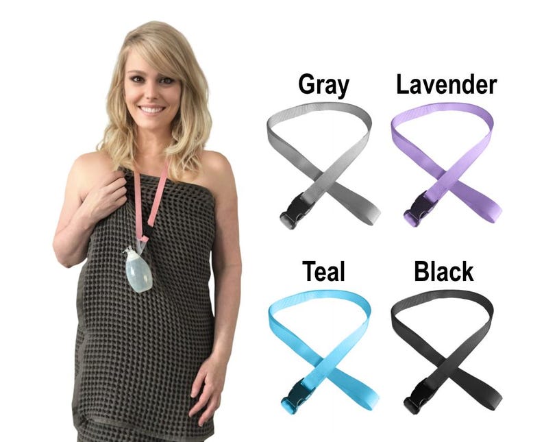 Puede incluir: Una colecci&oacute;n de correas de tela ajustables con hebillas de pl&aacute;stico de liberaci&oacute;n lateral, disponibles en gris, lavanda, verde azulado y negro. Cada correa presenta un dise&ntilde;o de bucle y se muestra junto a una prenda envolvente gris oscuro.