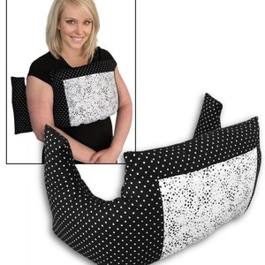 May include: A black and white polka dot pillow with a white square panel. The pillow is designed to be worn around the neck and shoulders. An additional smaller pillow is also visible. The design is a mix of polka dots and a white, speckled pattern.