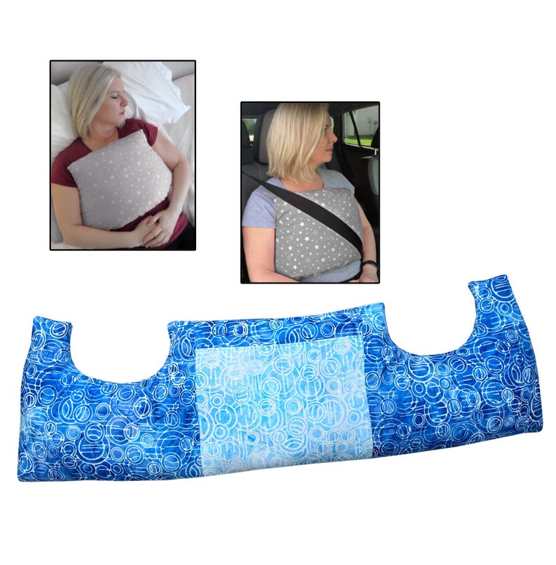 May include: A blue and white patterned pillow with a unique shape, designed for comfort. The pillow is shown in use in a car and while sleeping. The pillow has a light blue centre and a blue and white circular pattern on the sides.