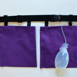 Puede incluir: Un cintur&oacute;n negro ajustable de nailon con hebilla de pl&aacute;stico y dos bolsas rectangulares de tela morada. Una pera de drenaje m&eacute;dica transparente con marcas de medici&oacute;n de hasta 100cc est&aacute; conectada a una bolsa mediante un tubo flexible.