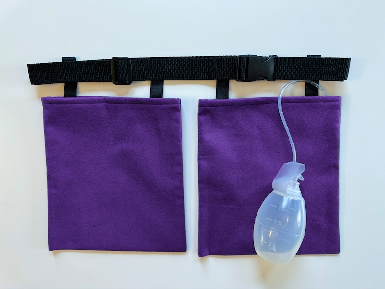 Puede incluir: Un cintur&oacute;n negro ajustable de nailon con hebilla de pl&aacute;stico y dos bolsas rectangulares de tela morada. Una pera de drenaje m&eacute;dica transparente con marcas de medici&oacute;n de hasta 100cc est&aacute; conectada a una bolsa mediante un tubo flexible.