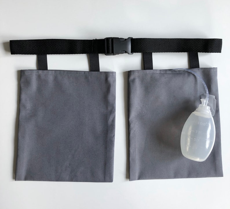 Puede incluir: Un soporte de tela gris para bolsas de drenaje m&eacute;dico con un cintur&oacute;n negro ajustable y hebilla de pl&aacute;stico. Dos bolsas rectangulares grises est&aacute;n unidas al cintur&oacute;n mediante correas negras. Una pera de drenaje m&eacute;dica transparente est&aacute; unida.