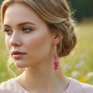 May include: Dangle earrings featuring stacked, irregular, polished pink gemstone chips suspended from silver-toned metal hooks. The earrings hang vertically, showcasing a vibrant, translucent pink hue with natural variations in the stone shapes.