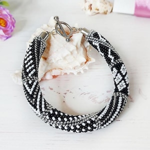 Può includere: Una tazza di ceramica bianca con manico nero e la scritta "But First, Coffee" in nero, in grassetto. La tazza è su una superficie bianca.