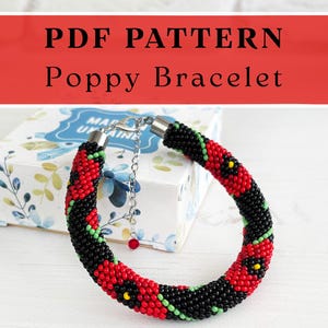 May include: A beaded bracelet featuring a repeating pattern of red poppy flowers with yellow centers on a black background, accented with green stems. The bracelet includes a silver-tone metal clasp and an adjustable chain with a small red bead.