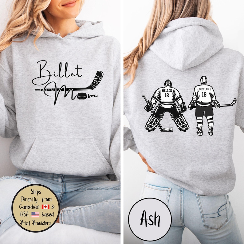 May include: Light grey hoodie with a front graphic that reads "Billet Mom" with a hockey stick design. The back features hockey player graphics with the name "MELLON" and numbers 12 and 16. The hoodie is ash-colored.