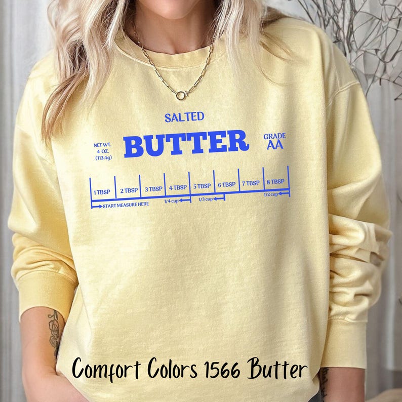 May include: A yellow sweatshirt with the text "SALTED BUTTER GRADE AA" and a measurement guide for tablespoons of butter. The text "Comfort Colors 1566 Butter" is printed on the bottom of the sweatshirt.