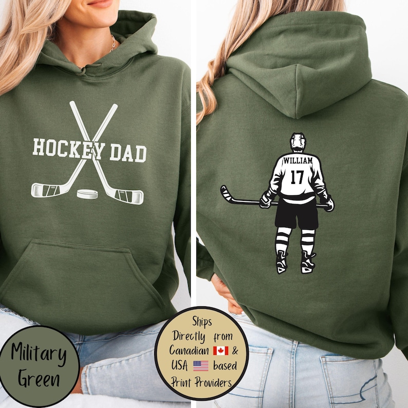 Puede incluir: Sudadera con capucha verde militar con el texto "HOCKEY DAD" y palos de hockey en la parte delantera. La parte trasera presenta un gr&aacute;fico de jugador de hockey con el nombre "William" y el n&uacute;mero "17".