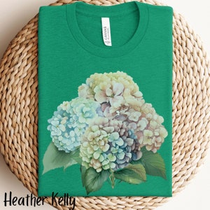 May include: A green t-shirt with a watercolor illustration of a bouquet of blue, white, and purple hydrangeas.