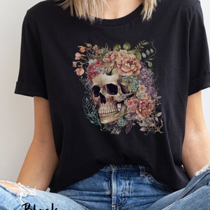 May include: Black t-shirt with a floral skull design. The skull is surrounded by pink, purple, and blue flowers.