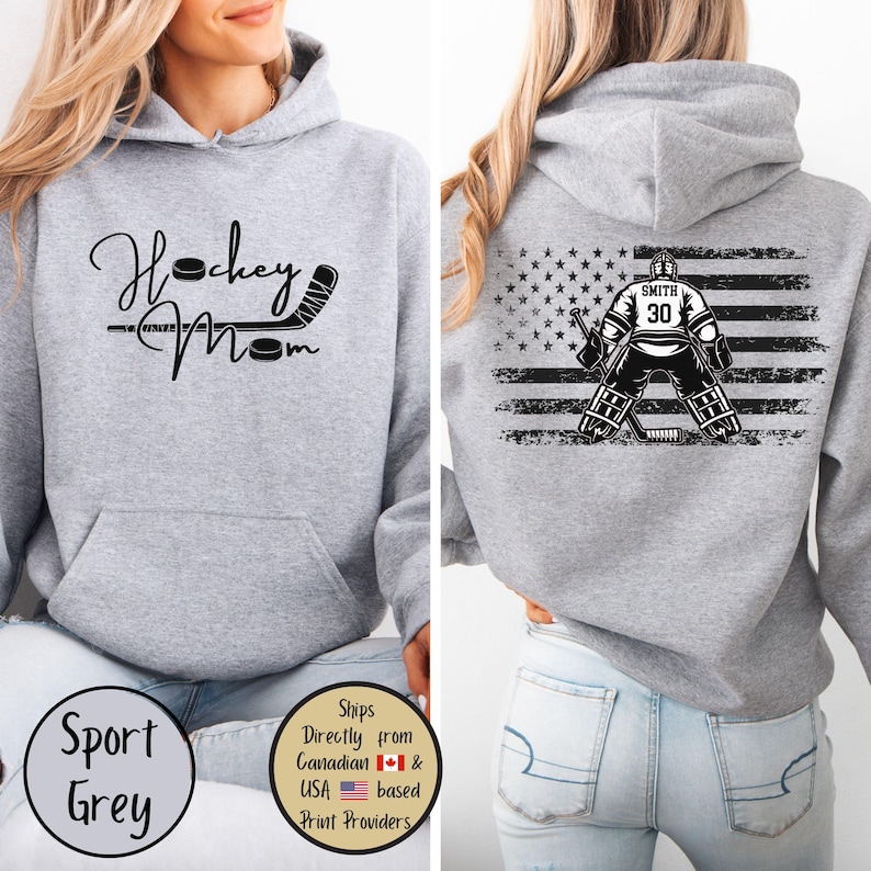 May include: Sport grey hoodie with "Hockey Mom" text and hockey stick graphic on the front. The back features a hockey goalie graphic with the American flag and the name "Smith" and number "30".