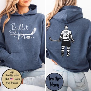 May include: Heather navy blue hoodie with a front graphic that says "Billet Mom" with a hockey stick and puck. The back of the hoodie features a hockey player graphic with the number 12 and the word "Name".