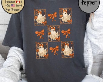May include: Dark gray t-shirt featuring a repeating pattern of cartoon ghosts with orange bows and pumpkins. The design is framed with orange borders and decorative elements. The word "Pepper" is printed on the upper right.