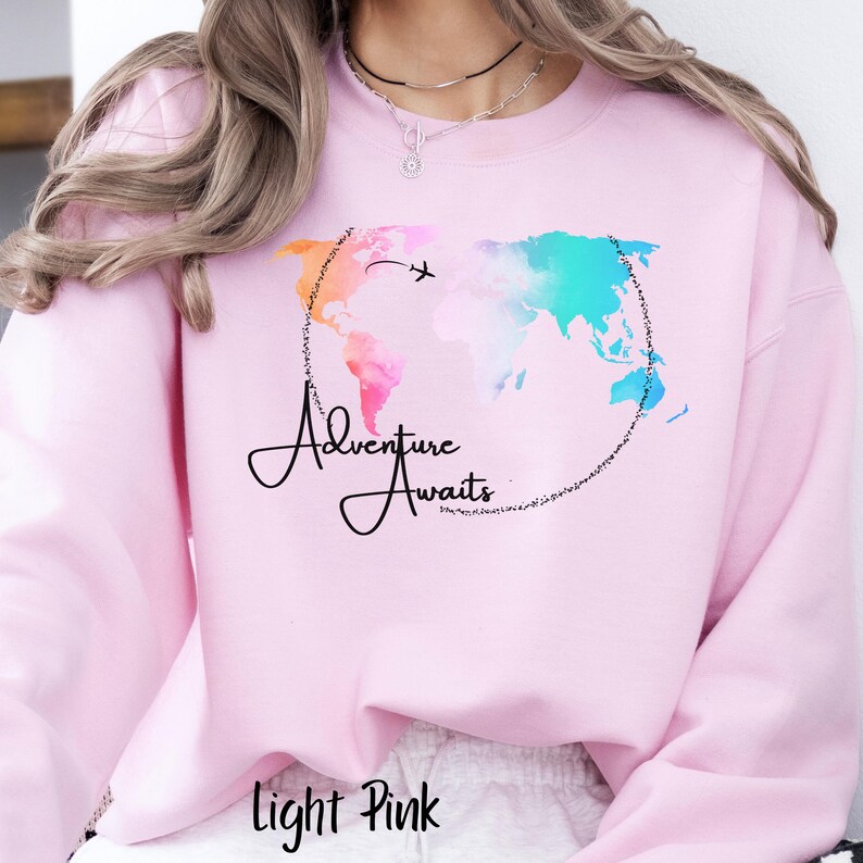 May include: Light pink sweatshirt with a watercolor world map design and the text "Adventure Awaits".