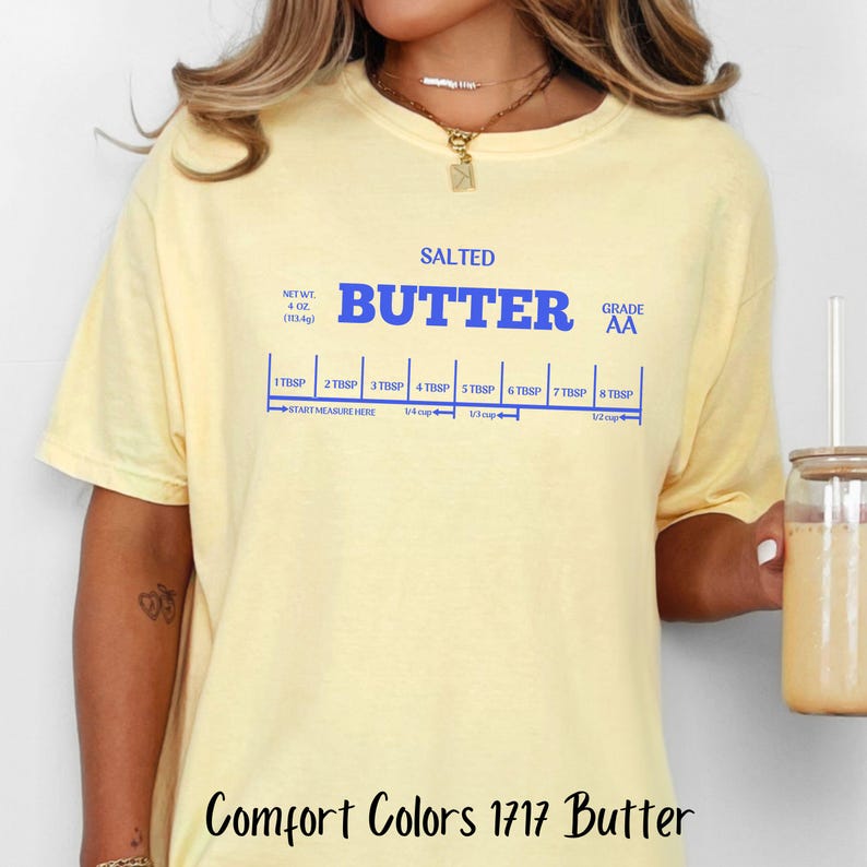 May include: A yellow t-shirt with a blue graphic of a stick of butter with the words "SALTED BUTTER GRADE AA" and a measurement guide in tablespoons and cups.