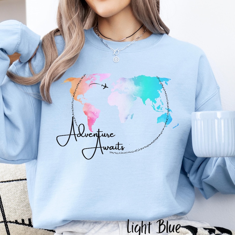 May include: Light blue sweatshirt with a watercolor world map design and the text "Adventure Awaits".