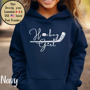 May include: Navy blue hoodie with the words "Hockey Girl" in white script, along with a hockey puck and stick graphic. The hoodie has a front pocket and a hood. The word "Navy" is printed at the bottom left.