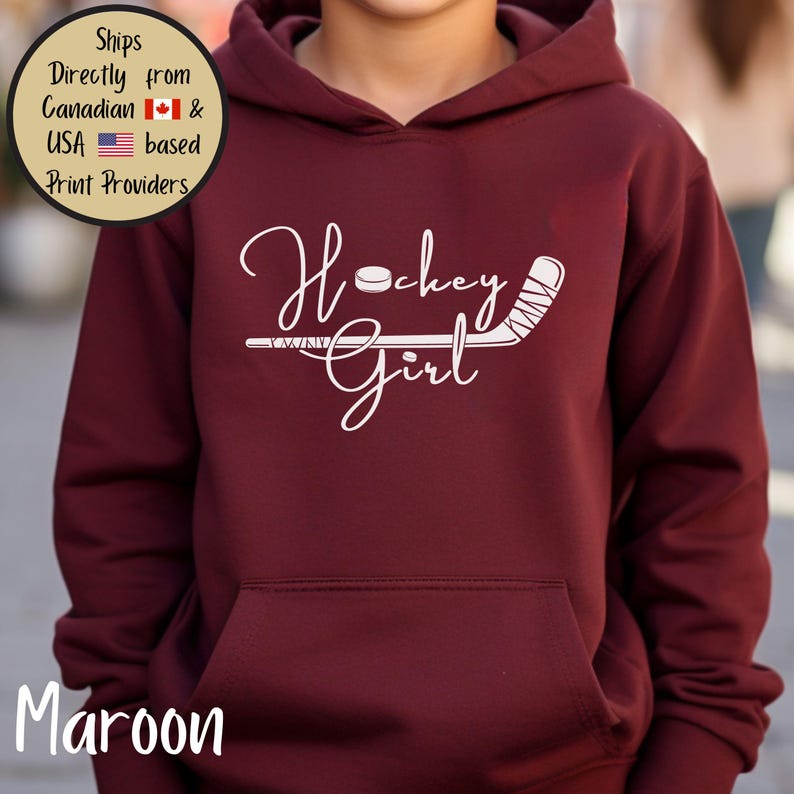 May include: Maroon hoodie with a white "Hockey Girl" design featuring a hockey puck and stick. The hoodie has a front pocket and a hood. The word "Maroon" is printed at the bottom of the image.