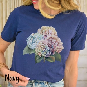 May include: A navy blue t-shirt with a floral print of hydrangeas in shades of pink, blue, and white.